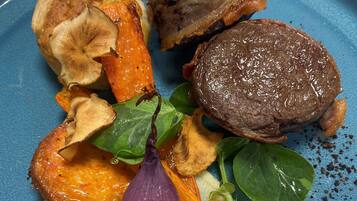 Um prato com bife, batatas assadas e cebola vermelha.