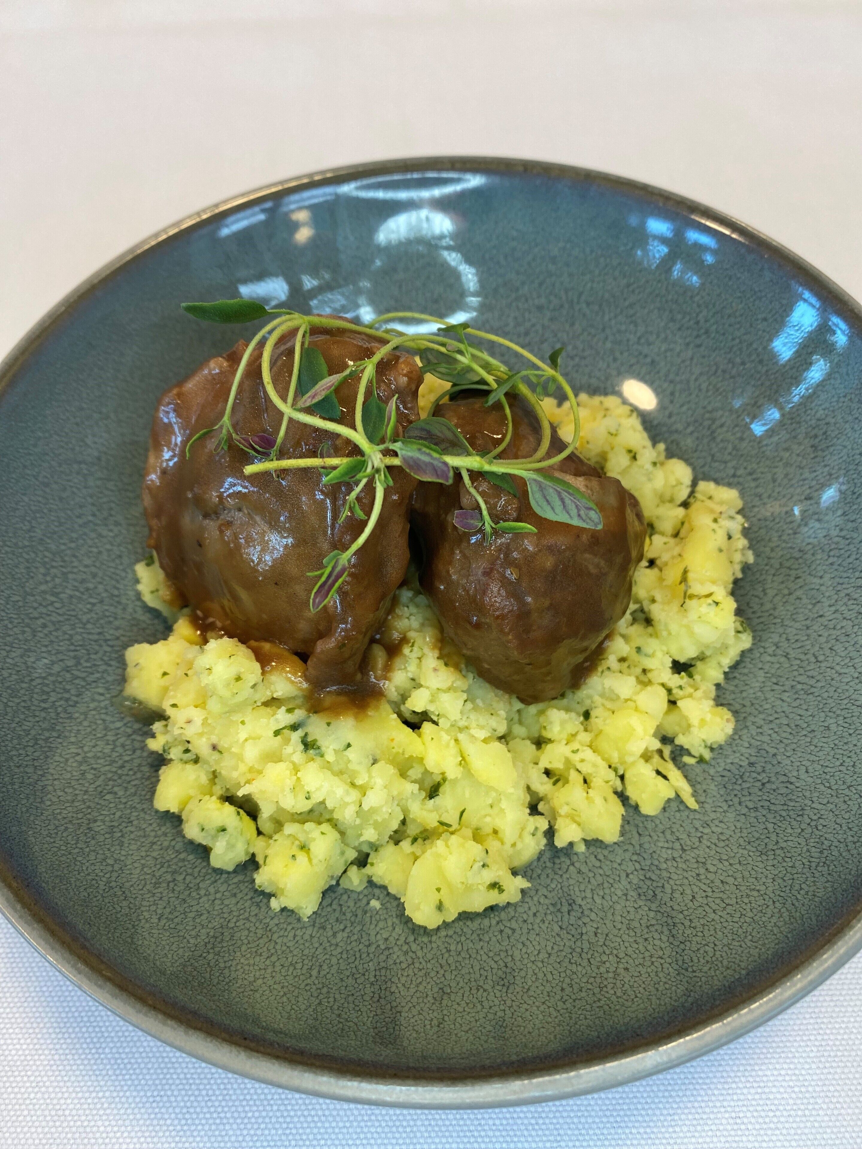 A plate with two meatballs and mashed potatoes.