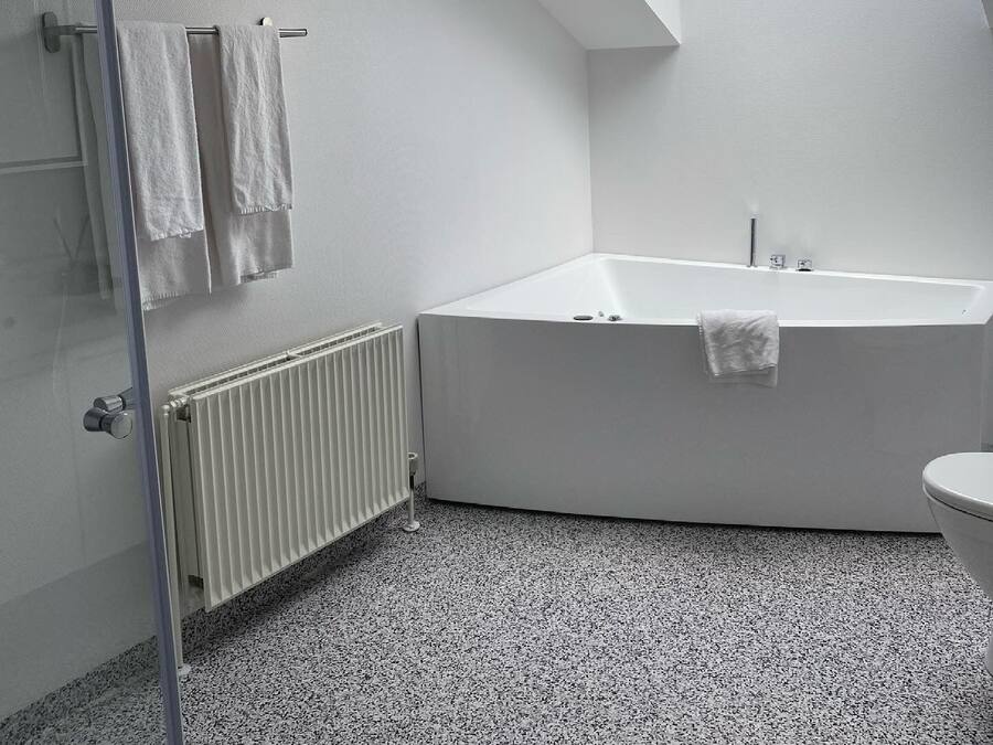 Un bagno moderno con finestra a soffitto, una vasca freestanding, un water e un box doccia in vetro.