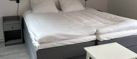 A bedroom with a bed, bedside tables, and a small white table.