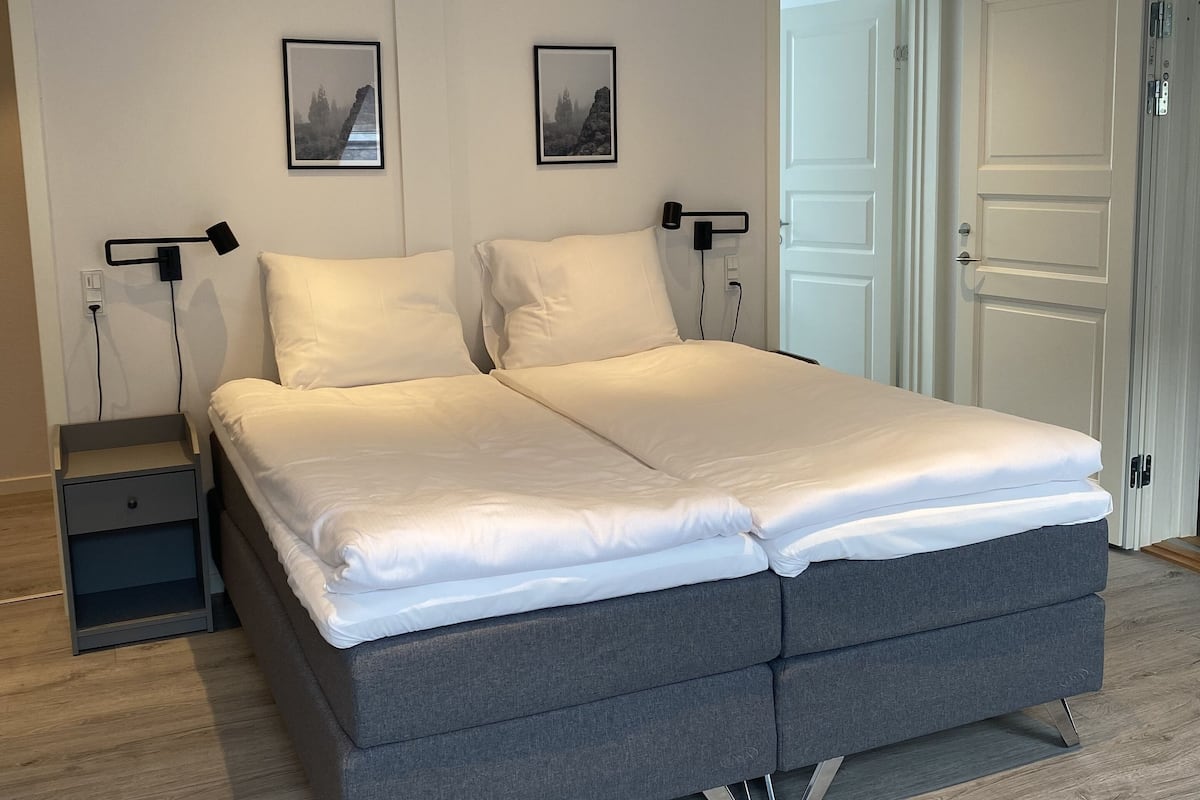 Un dormitorio moderno con una cama grande, mesitas de noche y dos cuadros enmarcados en la pared.