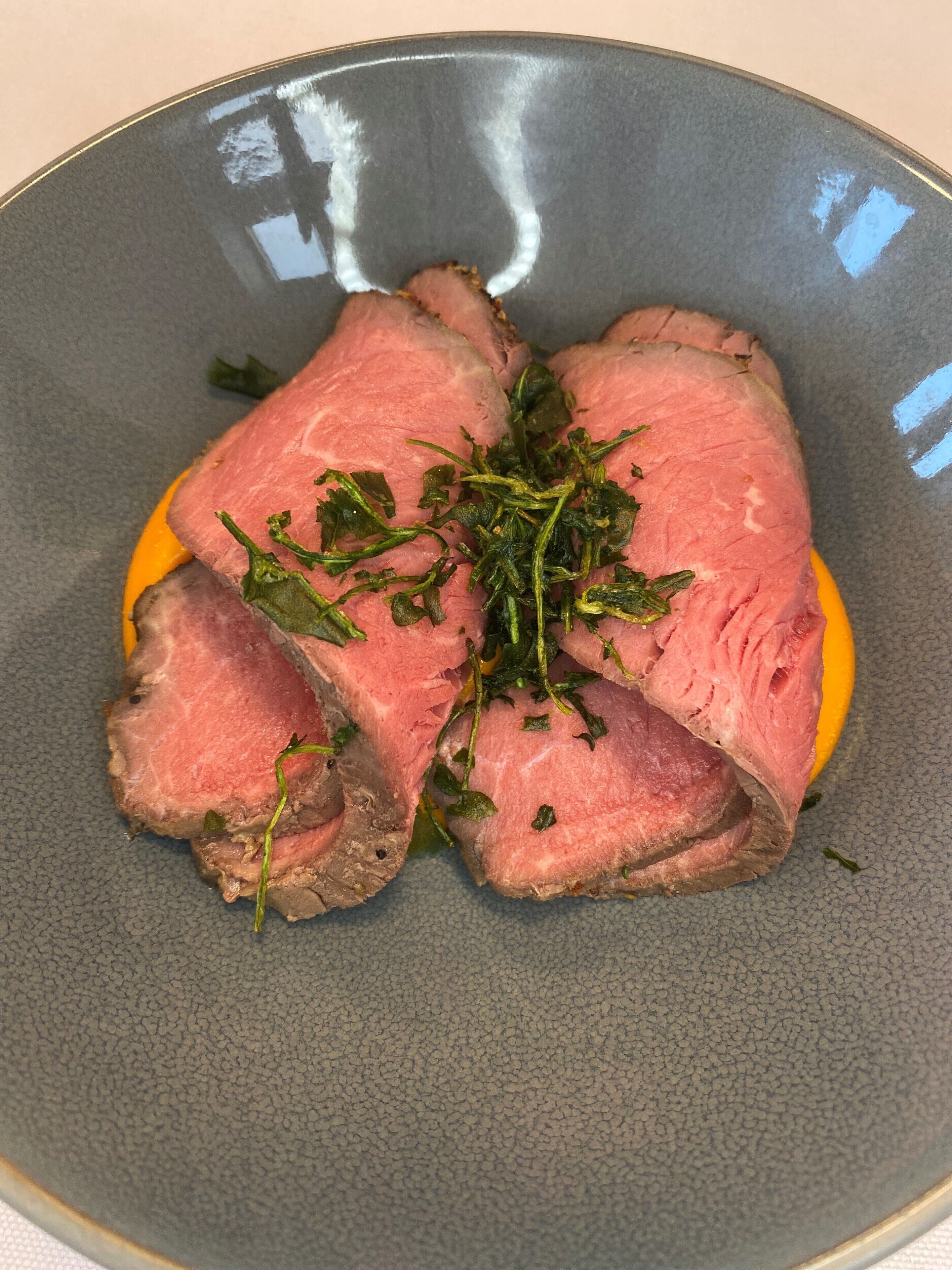 A plate of sliced meat with herbs.