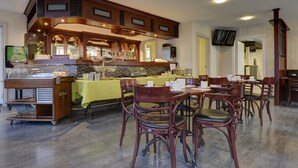 Un restaurante con zona de bar, sillas de madera y mantel amarillo.