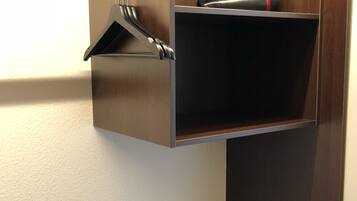 A corner of a room with a wooden cabinet and a metal towel rack.