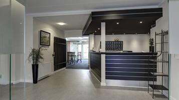 A modern reception area with a black counter, glass shelving, and a potted plant.