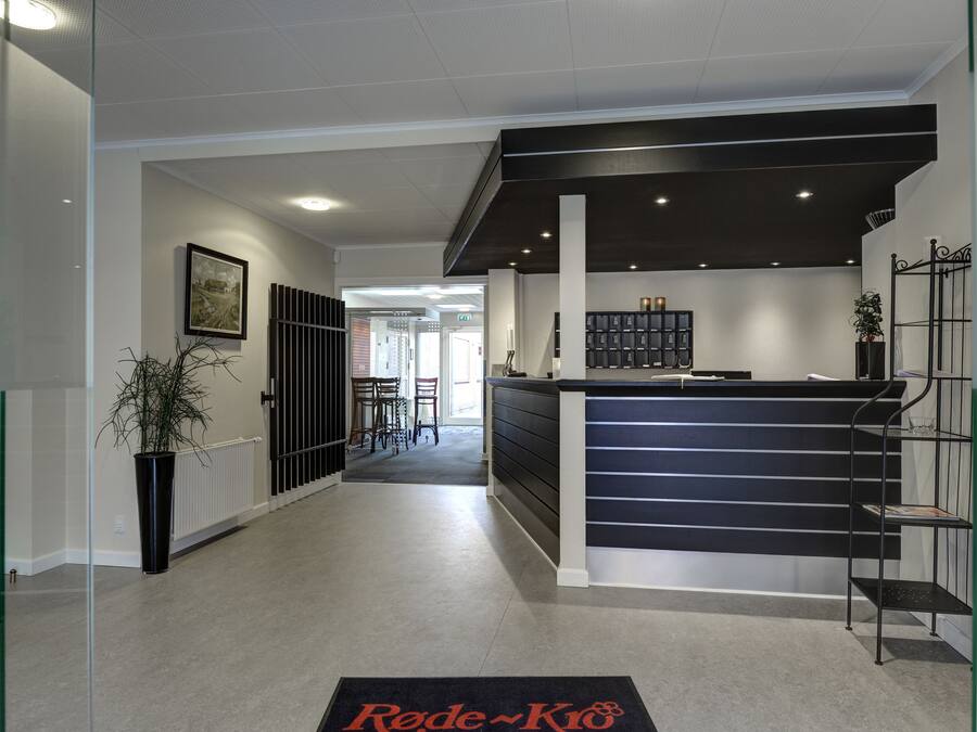 A modern reception area with a black counter, glass shelving, and a potted plant.