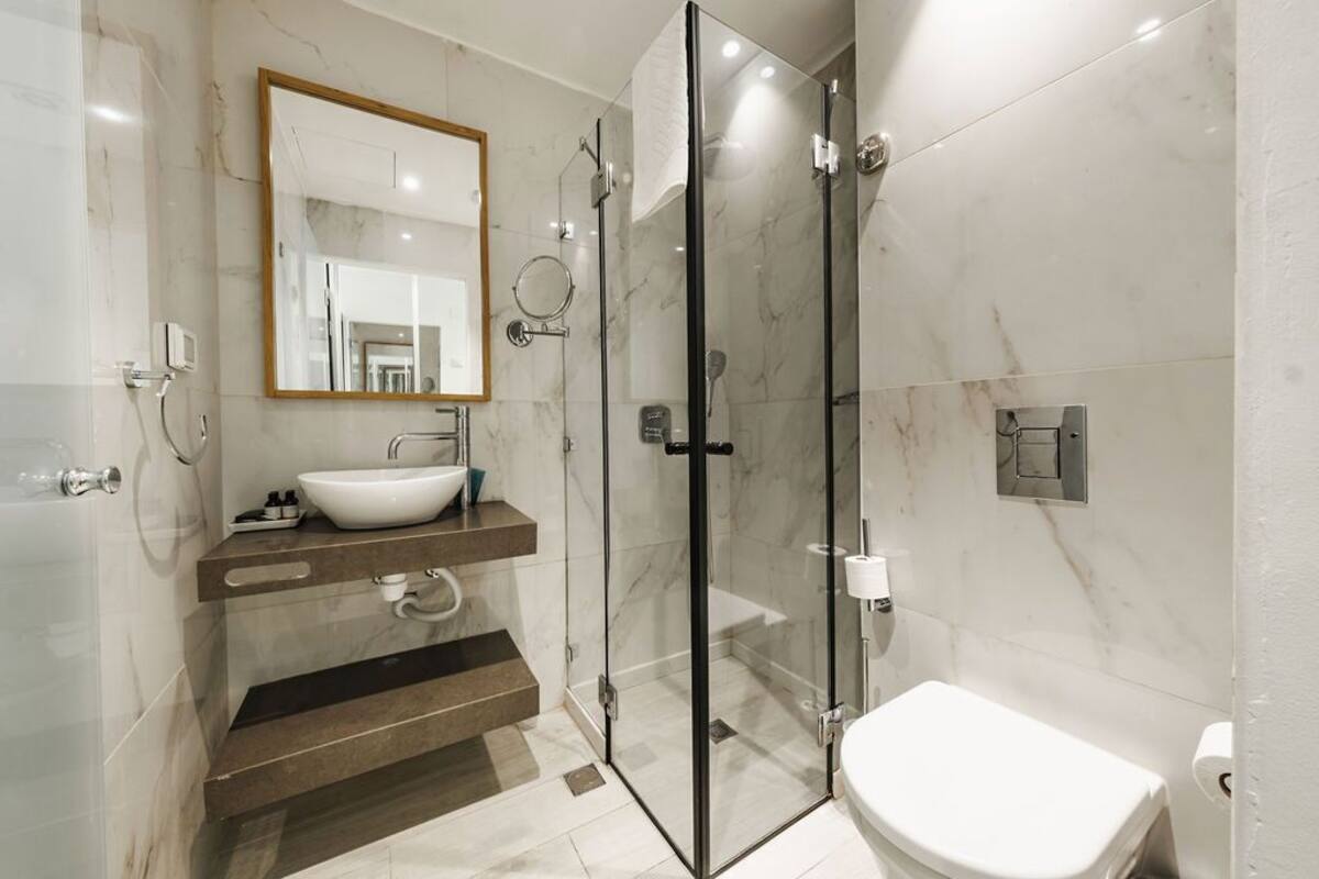 A modern bathroom with a glass-enclosed shower, a white sink, and a toilet.