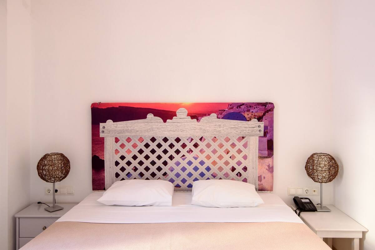 A neatly made bed with white bedding, a decorative headboard, and two bedside lamps.