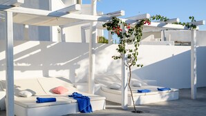 A white outdoor lounge area with cushioned seating and a pergola structure. - Atlas Boutique Hotel (Santorini)