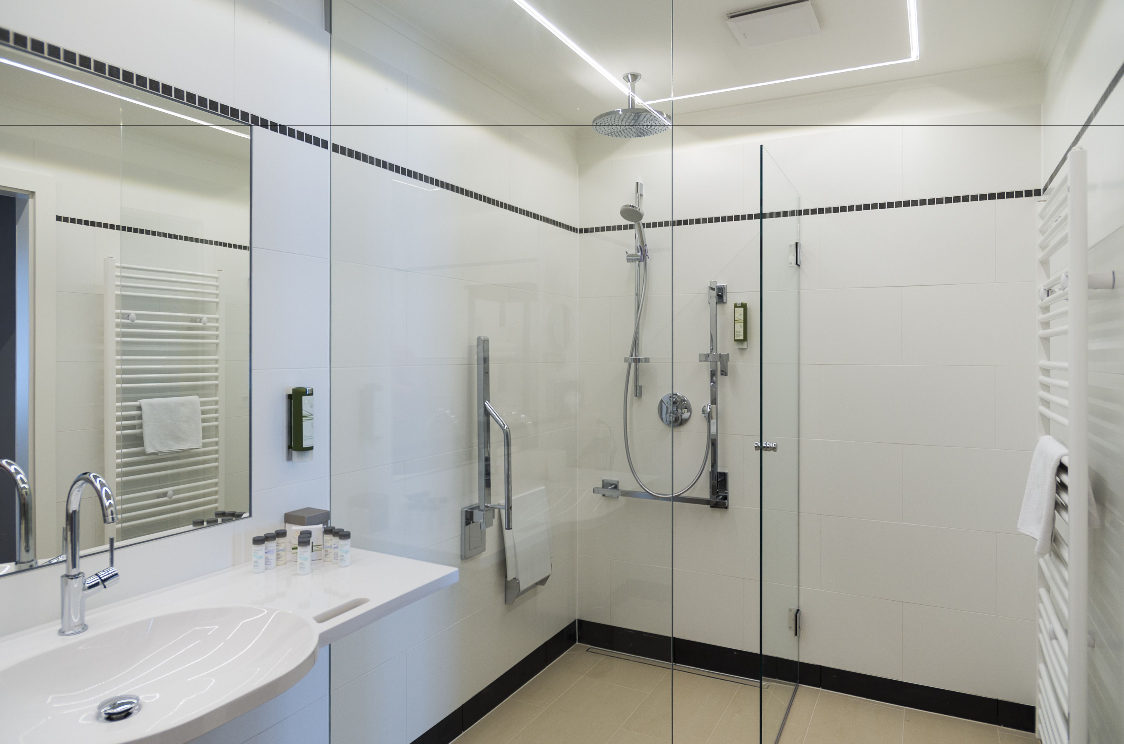 Un baño moderno con cabina de ducha de vidrio, un lavabo blanco y un espejo.
