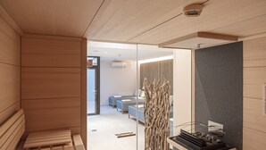 Una habitación de hotel moderna con un banco de madera, un separador de vidrio, un sofá y una escultura decorativa de un árbol.