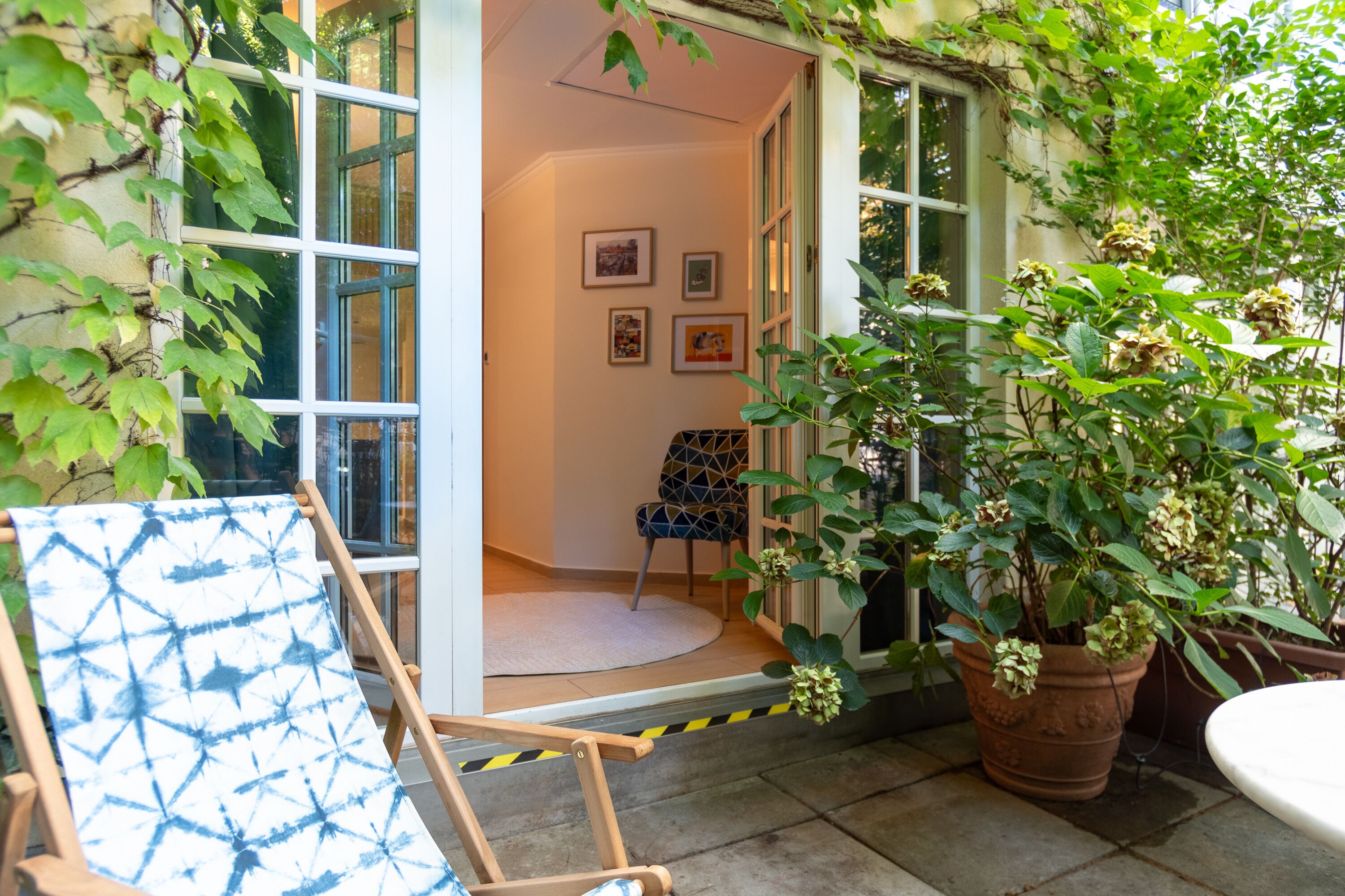 Une pièce avec une grande fenêtre, une chaise et une plante en pot.