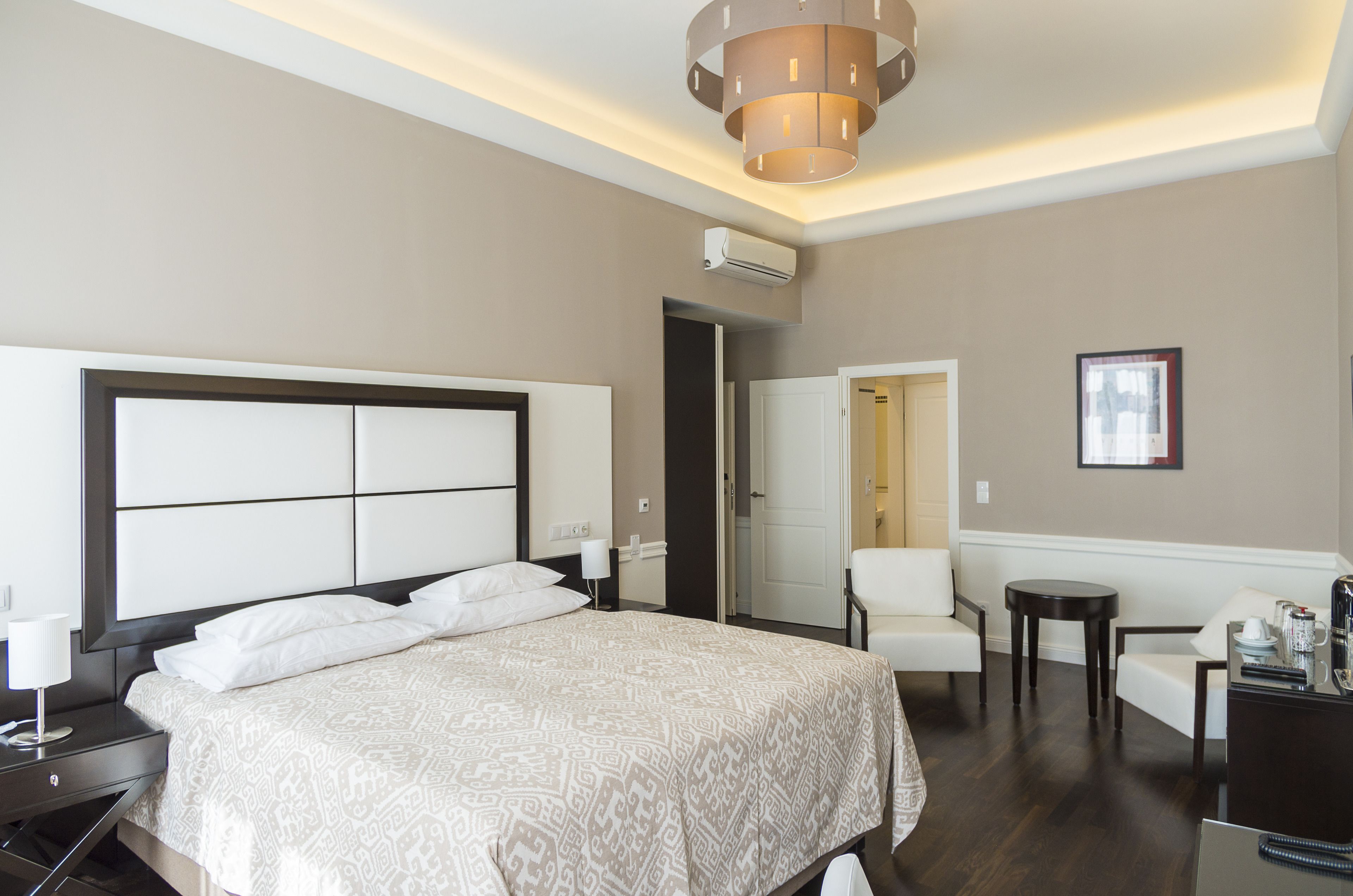 Camera d'albergo con un letto grande, un comodino, una sedia, un tavolino e una scrivania.