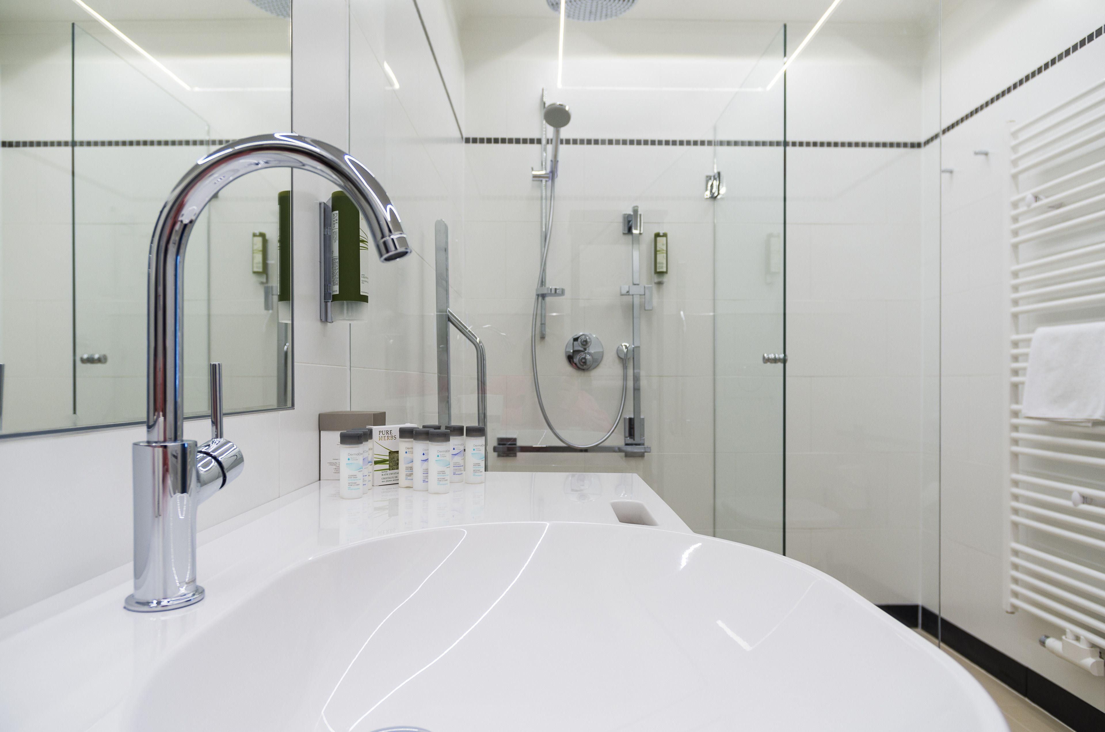 Un baño moderno con un lavabo blanco grande, grifería cromada y cabina de ducha de vidrio.