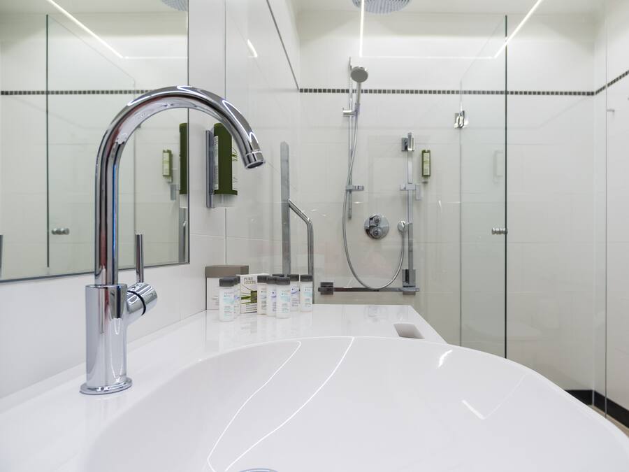 Un baño moderno con un lavabo blanco grande, grifería cromada y cabina de ducha de vidrio.