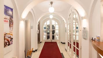 A hotel corridor with white walls, a red carpet, and arched ceilings.