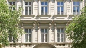 Un edificio de varios pisos con estilo arquitectónico clásico, que presenta ventanas simétricas y molduras decorativas.