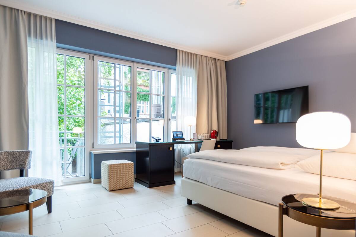 A modern hotel room with a large bed, a desk, and a chair.