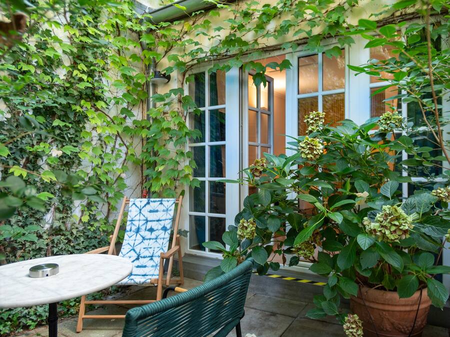 A patio with a table, chairs, and a potted plant.