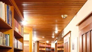 Een bibliotheek met houten boekenplanken, een kamerbreed tapijt met dessin en een houten plafond.