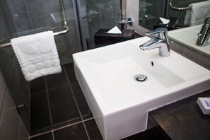 A modern bathroom with a white sink, chrome faucet, and a glass shower enclosure.