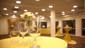 A round table with two champagne flutes and a glass of water, set on a yellow tablecloth in a well-lit room with multiple tables and chairs.