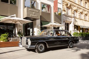 A classic black car parked in front of a building with a sign reading "BRASSERIE BAKERY".