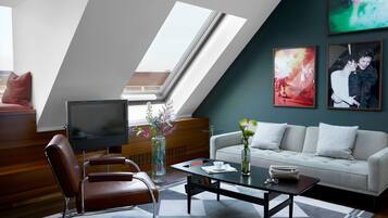 A modern living room with a sofa, a coffee table, a TV, and artwork on the walls.