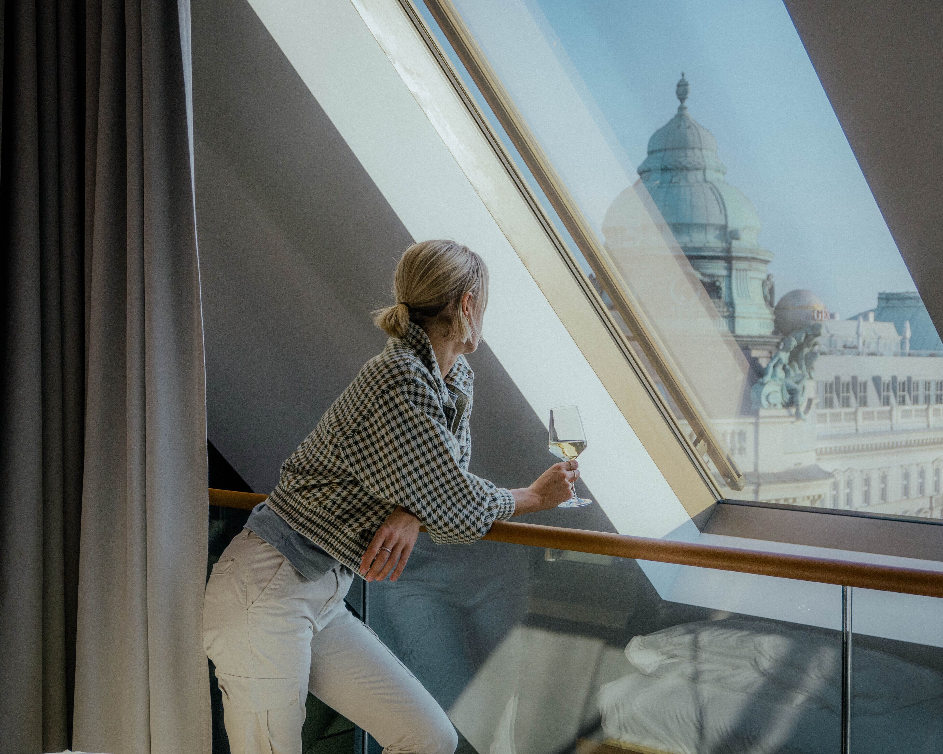 Una persona sentada junto a una ventana con vistas a un edificio con cúpulas.