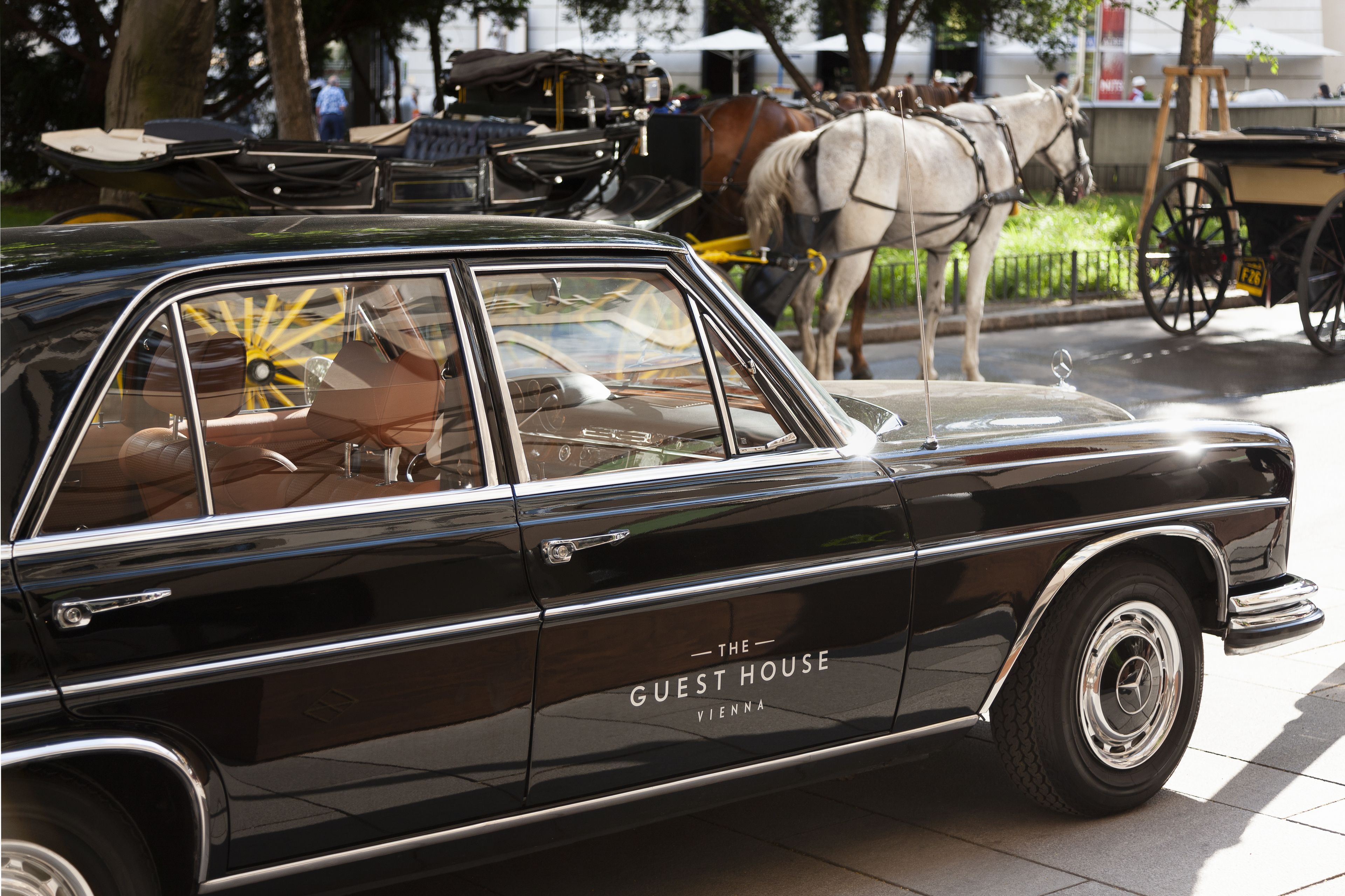 A classic black car with the text "The Guest House Vienna" on its side.