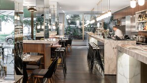 Un restaurante moderno con una barra alargada, taburetes y vistas a la calle.