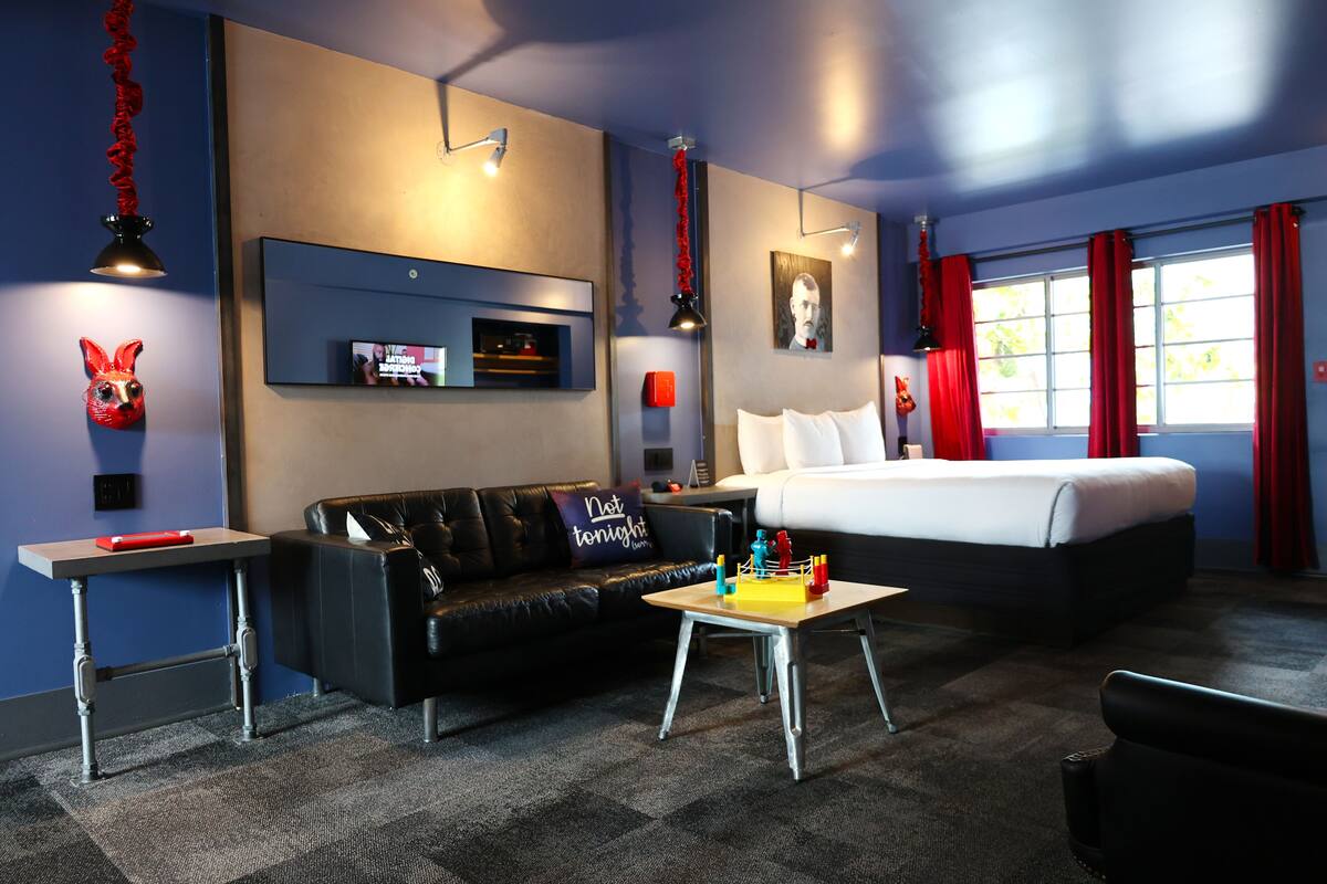 Une chambre d’hôtel moderne équipée d’un lit, d’un canapé, d’une petite table et d’un téléviseur fixé au mur.