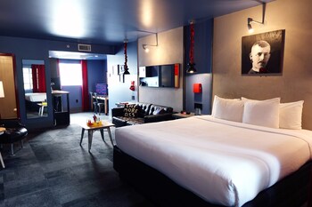 A bar area with a red floral wallpaper, multiple stools, and a bar counter with various items. at Hotel Gaythering - Gay Hotel - All Adults Welcome