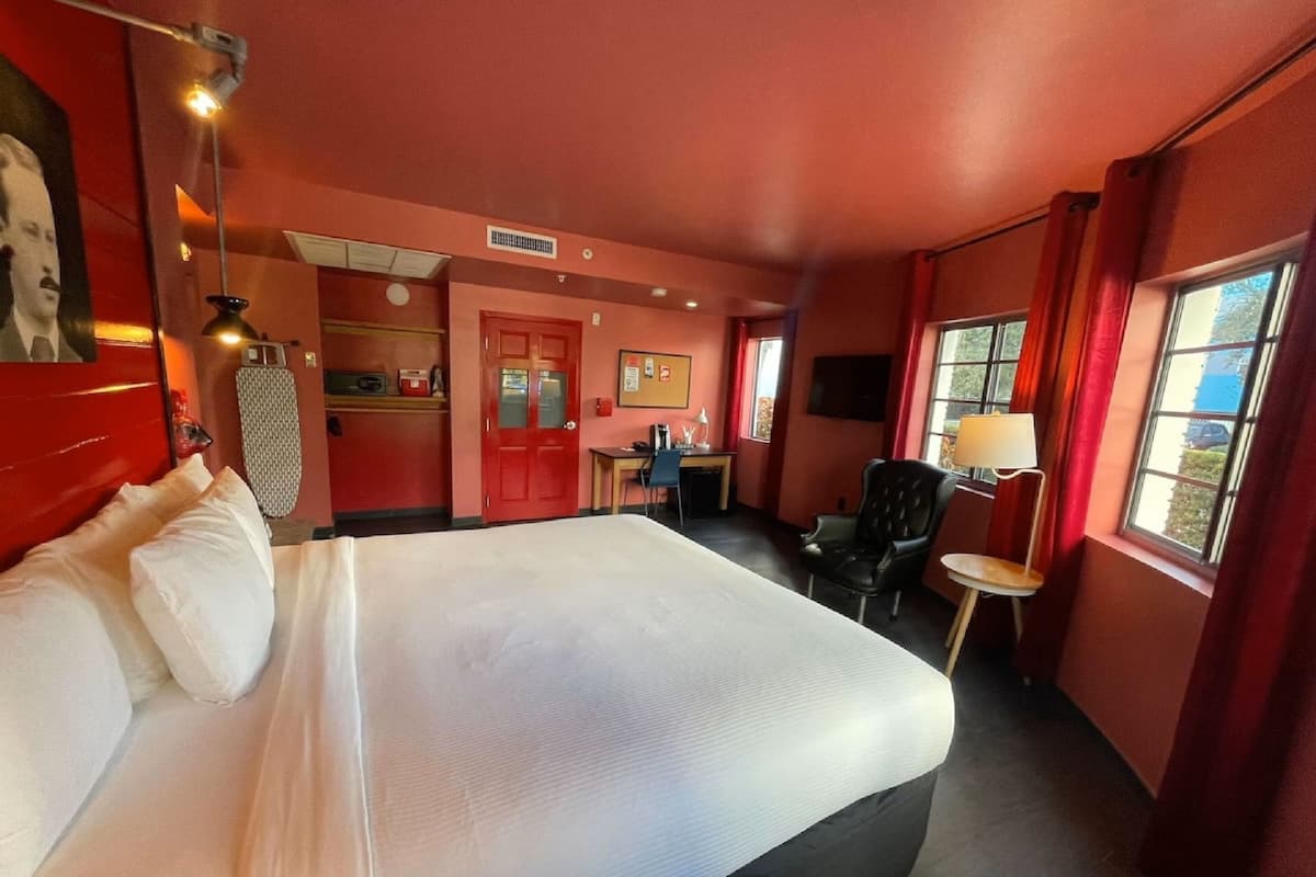 Une chambre d’hôtel avec un grand lit, un bureau, une chaise et un téléviseur.