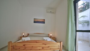 Een houten bed met twee nachtkastjes, een wandairconditioner en een schilderij boven het bed.