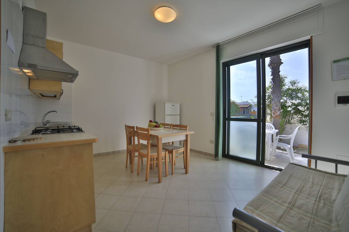 A modern kitchen with a gas stove, wooden cabinets, and a dining area with a table and chairs.