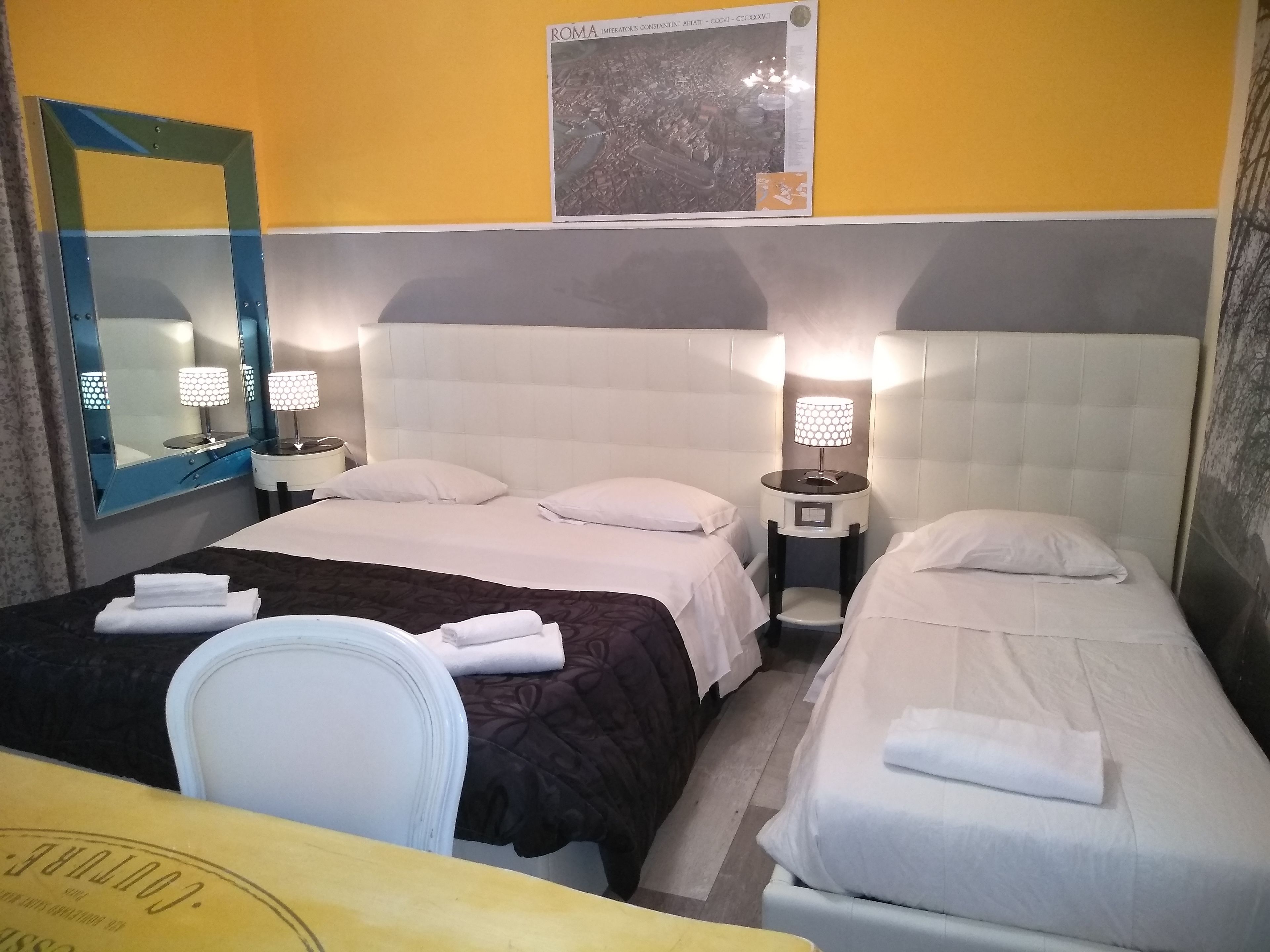 Une chambre d’hôtel avec deux lits, un grand miroir et un tableau encadré au mur.