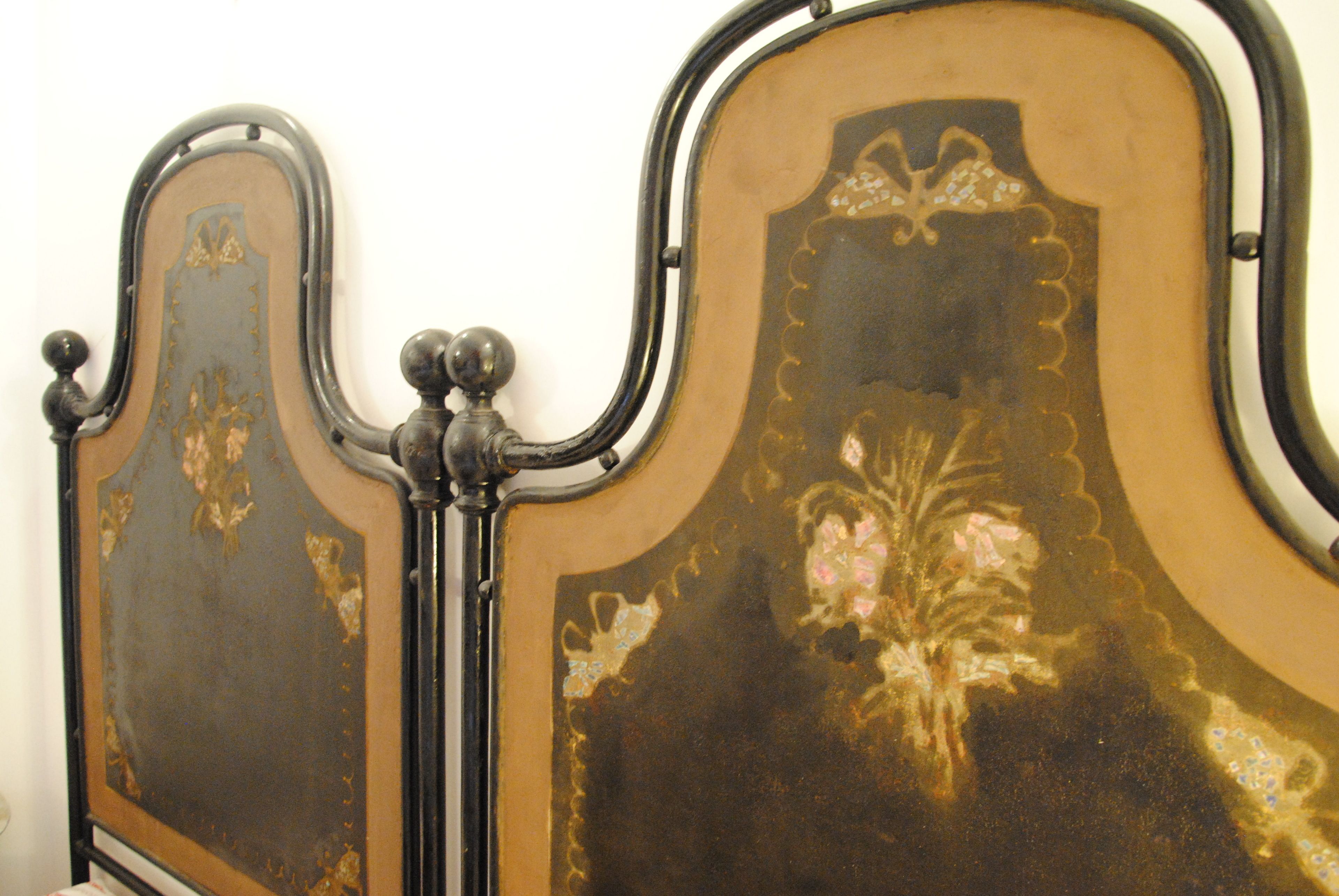 A bed with a dark headboard and floral design.