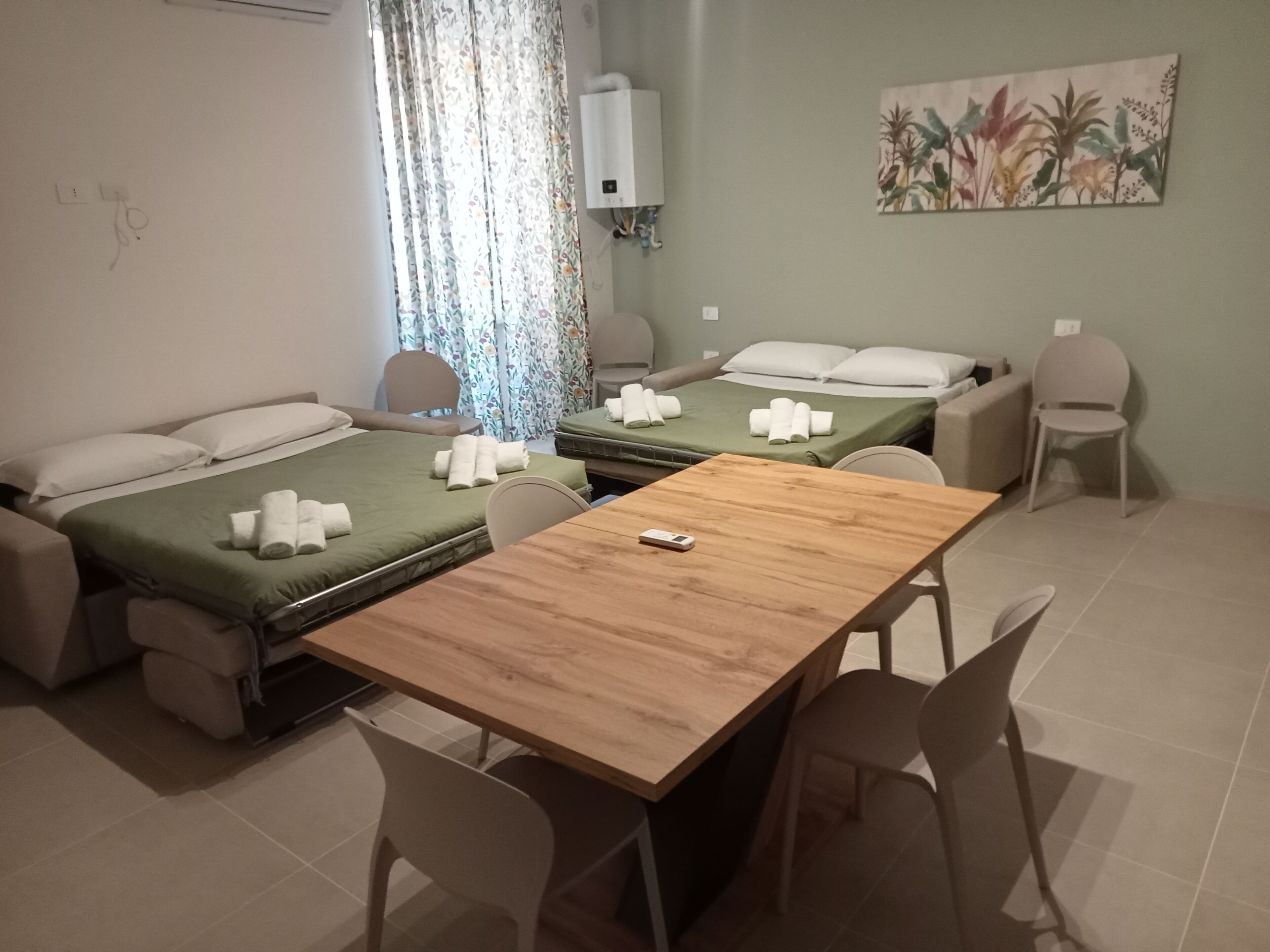 Una habitación de hotel con dos camas, una mesa de madera y una silla.