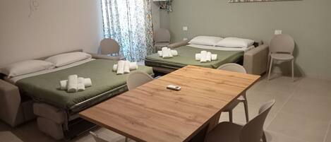 Una habitación de hotel con dos camas, una mesa de madera y una silla.