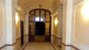 A corridor with a marble floor, arched ceiling, and wall sconces. - White Vatican (Rome)