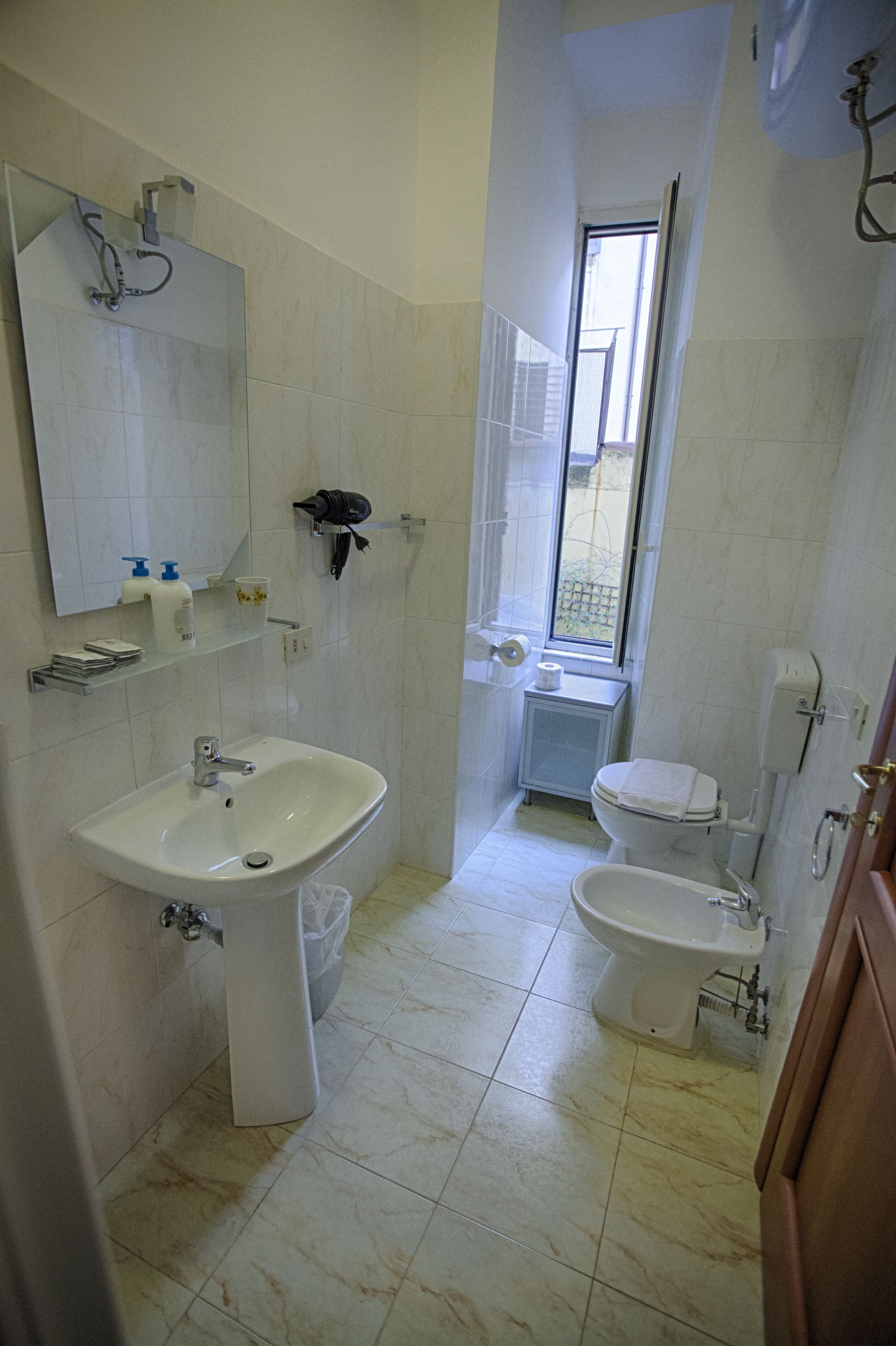 A bathroom with a sink, toilet, bidet, and a mirror.