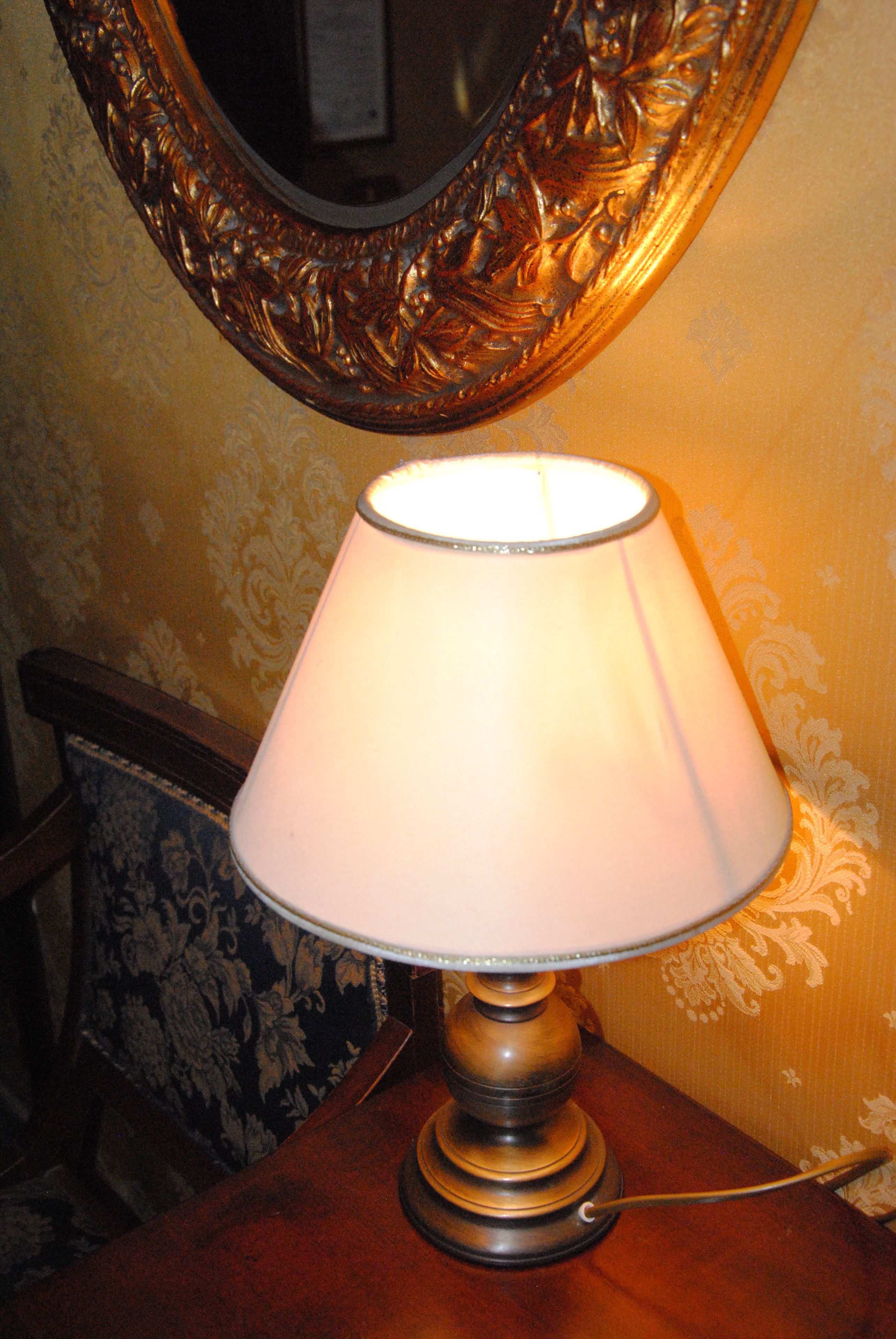 A table lamp with a white shade on a wooden table.