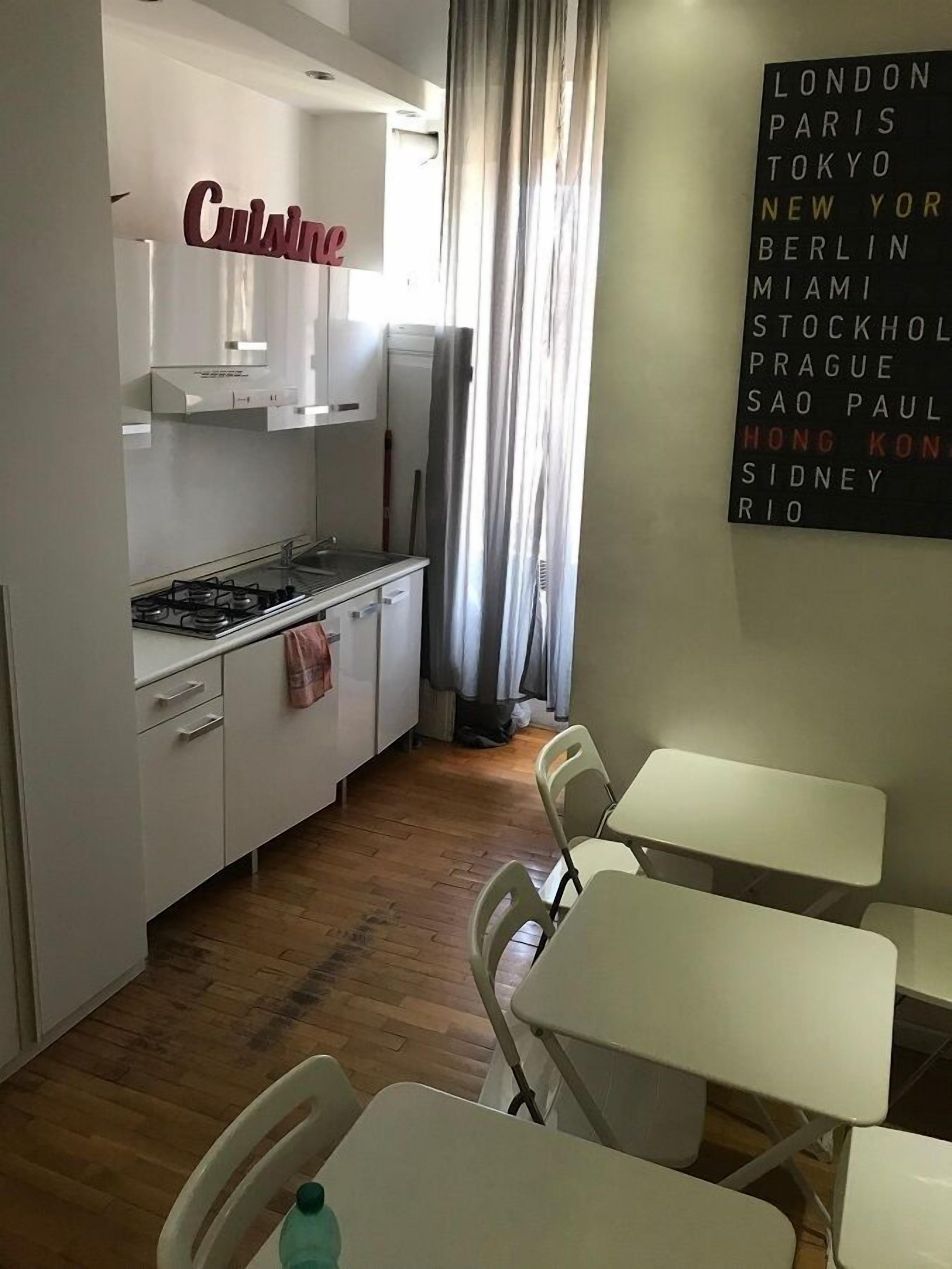 Una cocina compacta con estufa, pileta y alacenas, y un comedor con sillas y mesas.