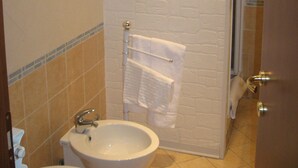 Un baño con un lavabo blanco, un inodoro, un perchero para toallas y un cuadro con una imagen de un barco en un muelle.