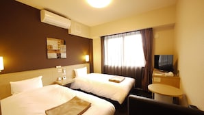 A hotel room with two beds, a desk, a TV, and a window with curtains.