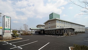 A hotel with a green sign, a parking lot, and a clear sky.