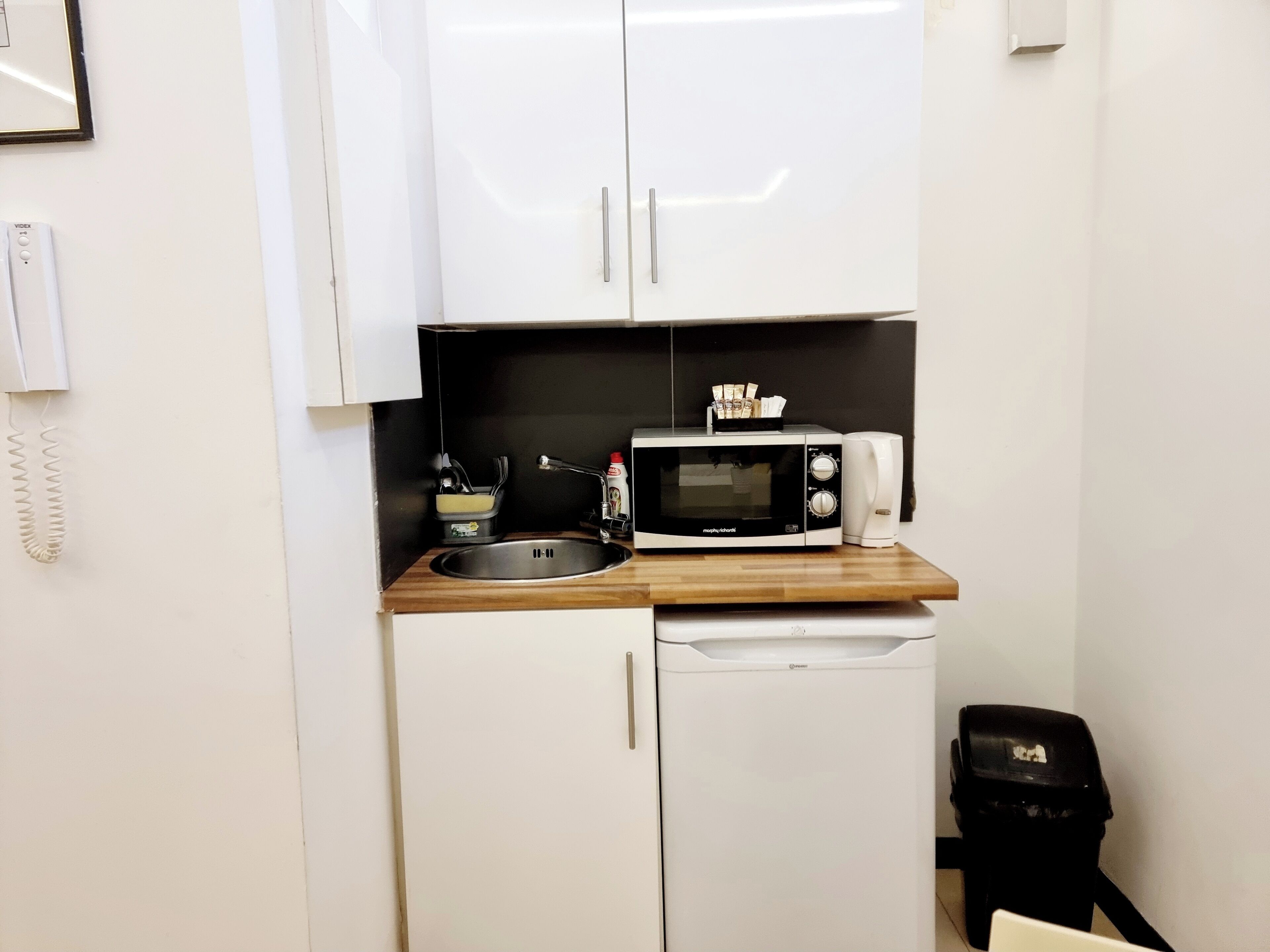 A compact kitchenette with a microwave, a small sink, and a dishwasher.