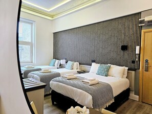 A hotel room with two beds, a wooden wardrobe, a desk, and a window with blinds. - London Stay Apartments (London)