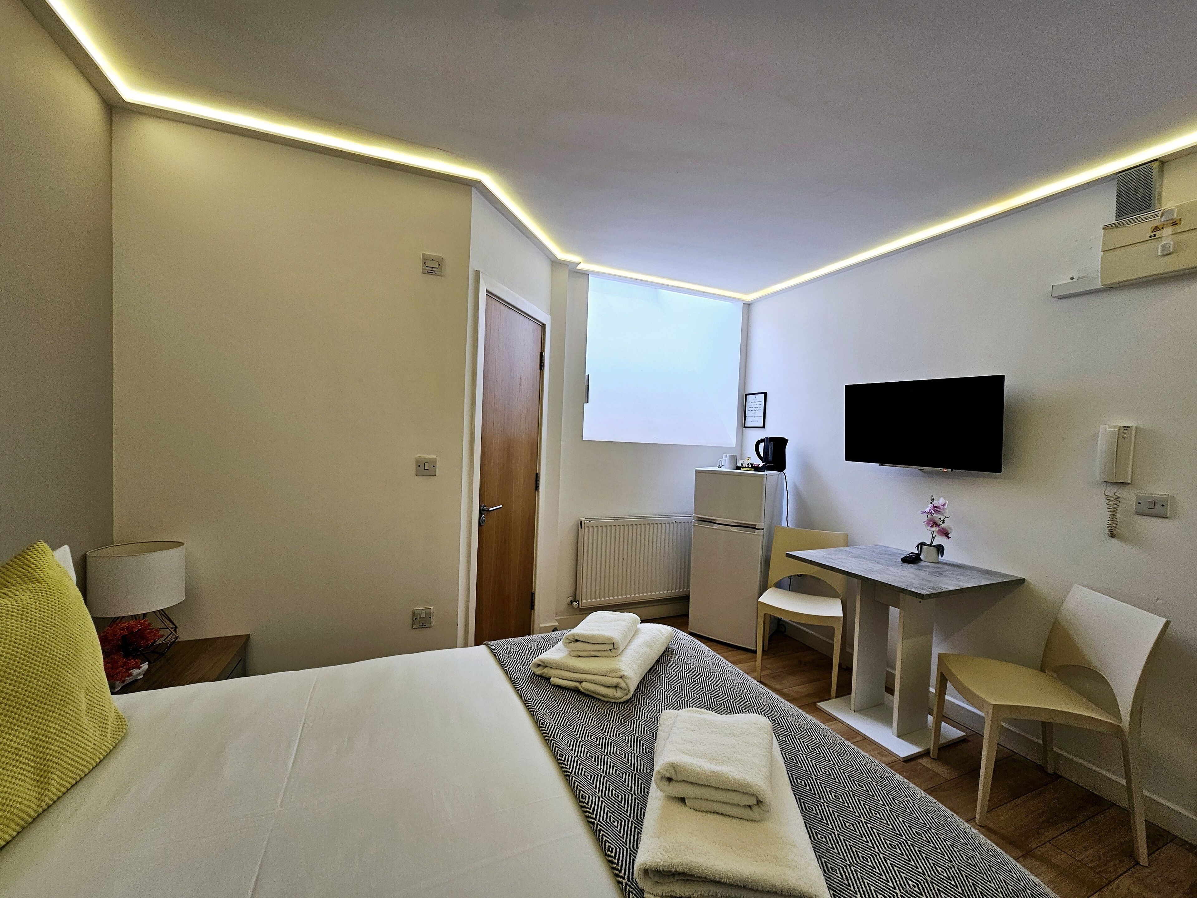 A hotel room with a bed, a desk, a chair, a television, and a radiator.